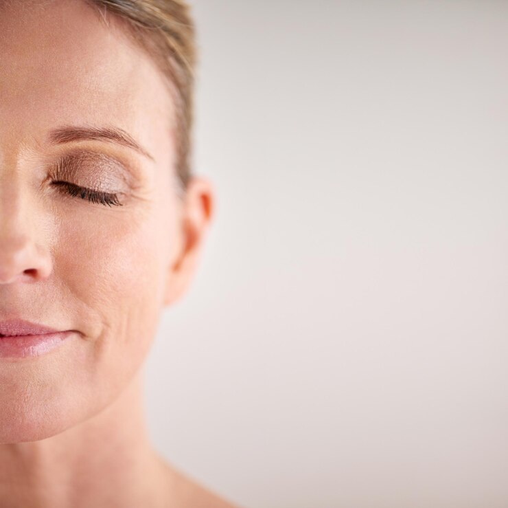 Foto maquete de beleza e meio rosto com uma mulher no estúdio em um fundo cinza para publicidade cosmética de cuidados com a pele bem-estar facial e olhos fechados com uma modelo feminina sênior posando para cuidados com a pele natural