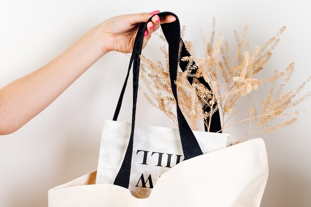 Maquete de bolsa de mão feminina de ecobag de algodão branco reutilizável com alças pretas com flores secas e ...