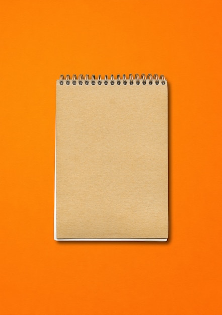 Foto maquete de caderno em espiral fechada, capa de papel marrom, isolado em laranja