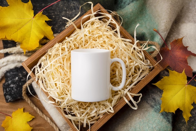 Maquete de caneca de café branco com caixa de presente de madeira rústica e folhas de bordo de outono. Caneca vazia simulada para promoção de design, modelo estilizado