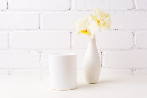 Maquete de caneca de café branco com suave orquídea amarela em vaso