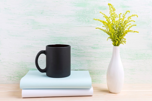 Maquete de caneca de café preta com grama verde ornamental