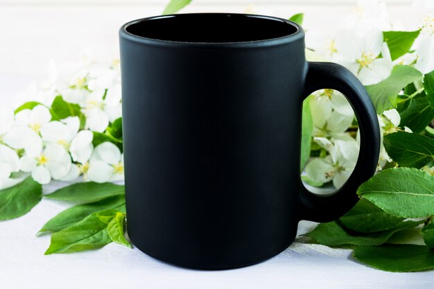 Maquete de caneca de café preto com flor de maçã