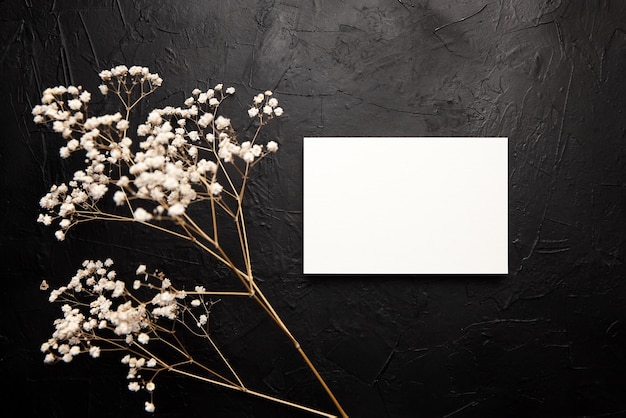 Maquete de cartão convite de casamento em branco com decoração floral branca em fundo preto maquete de cartão com flores secas na mesa