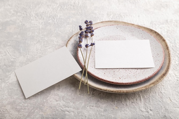 Maquete de cartão de convite de papel branco com lavanda em placa de cerâmica e espaço de cópia de vista lateral de fundo de concreto cinza
