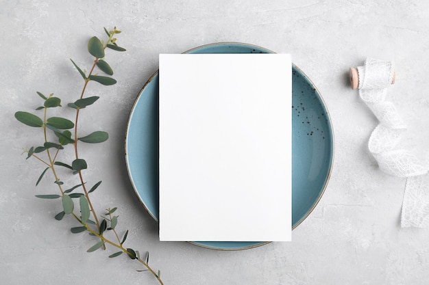 Maquete de cartão de convite de papelaria de casamento 5x7 em fundo cinza com eucalipto Maquete de cartão de menu com casamento festivo ou configuração de mesa de aniversário placa de cerâmica azul Maquete mínima de cartão em branco