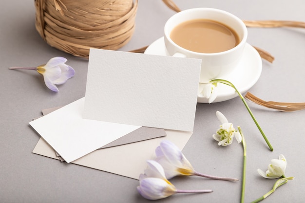 maquete de cartão de visita branco com flores de açafrão e galanto e uma xícara de café