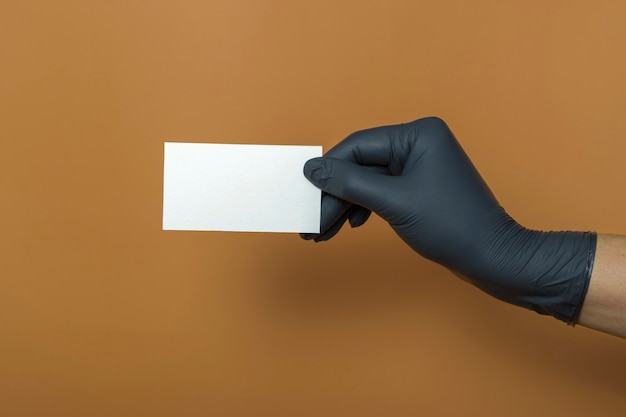 Maquete de cartão de visita branco sobre fundo colorido. Uma mão em uma luva médica segura um cartão de visita