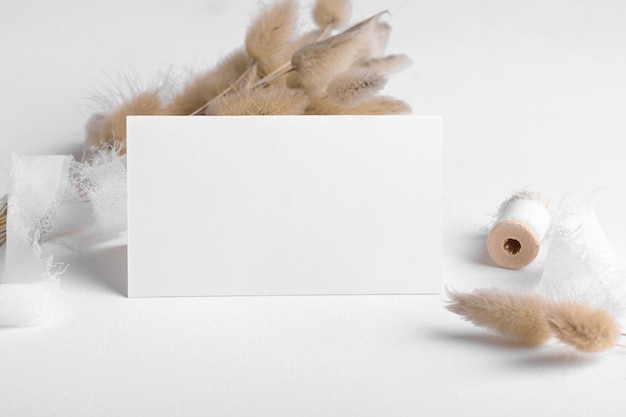 Maquete de cartão em branco dobrado de papelaria de casamento x tamanho no fundo da mesa branca com decoração boho