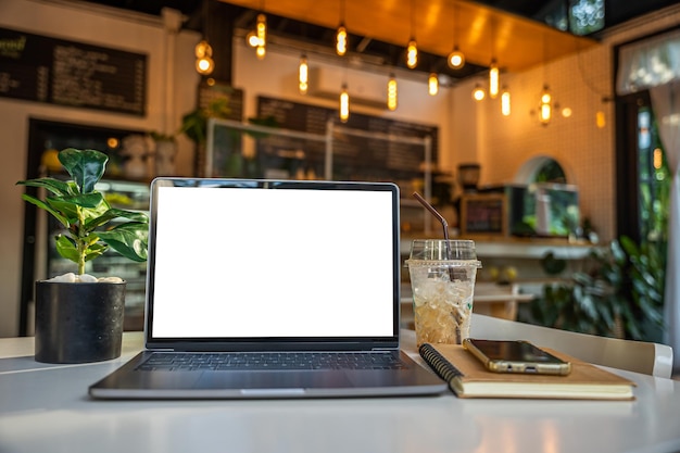 Maquete de computador portátil com tela vazia com notebookice café e smartphone no lado da mesa da janela do café na tela do caféWhite