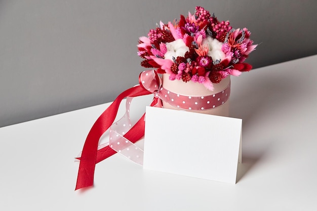 Maquete de convite ou cartão de felicitações e buquê de flores secas na mesa branca