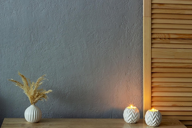 Maquete de decoração para casa parede de concreto pintada cinza vazia Há um vaso com grama seca e velas acesas na mesa Lugar para o seu texto