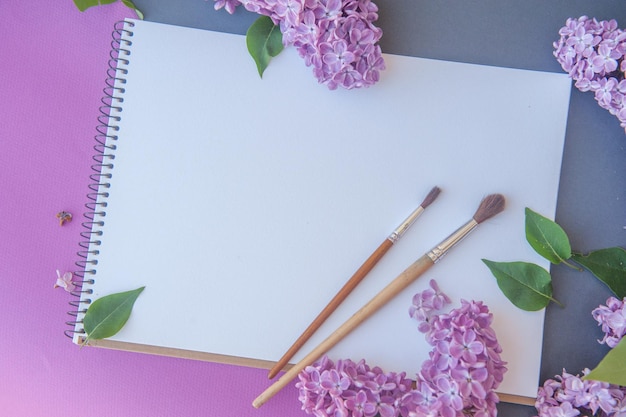 Maquete de fundo de primavera com caderno de desenho de espaço em branco vazio com flores violetas