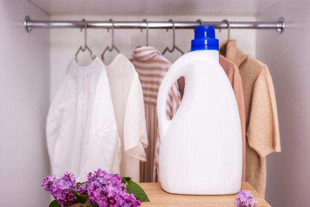 Foto maquete de garrafa de detergente branco no contexto de um guarda-roupa com roupas