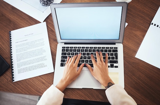 Foto maquete de laptop e mãos de mulher digitando proposta de relatório de negócios ou feedback no papel de cima escritor freelancer ou jornalista escrevendo artigo da web com pesquisa na internet e documentos no escritório