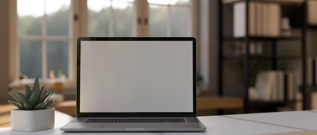 Maquete de laptop na mesa de trabalho branca sobre o fundo da sala de trabalho em casa turva