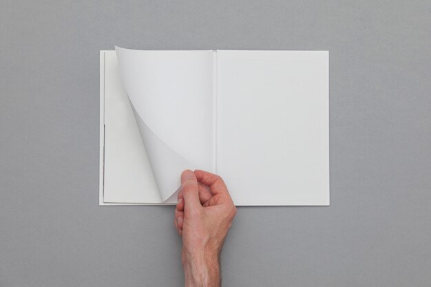 Maquete de livro Mão masculina segurando o livro em branco