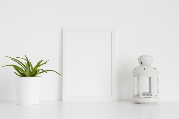 Maquete de moldura branca com uma planta suculenta e um castiçal em uma mesa branca Orientação de retrato