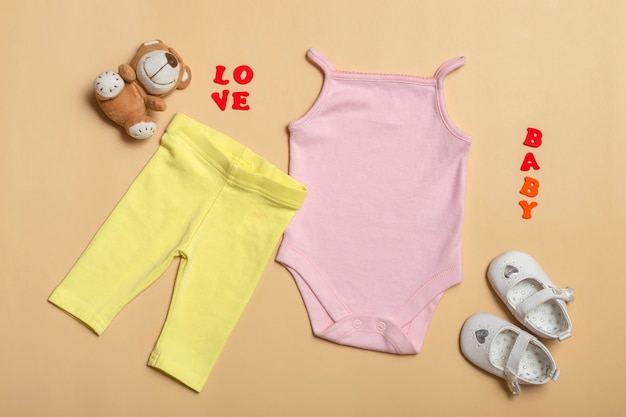 Maquete de postura plana de camisa rosa bebê, calça amarela, sapatos brancos com brinquedos em um fundo colorido. Layout para desenho e colocação de logotipos, publicidade.