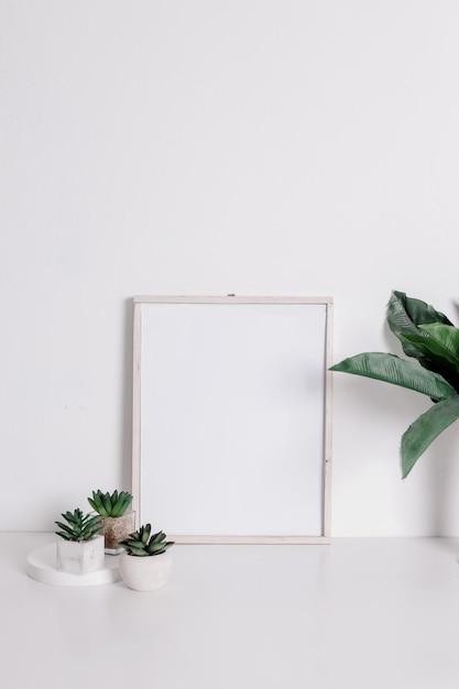 Maquete de quadro com flor artificial verde e suculenta em vasos no interior minimalista neutro quente