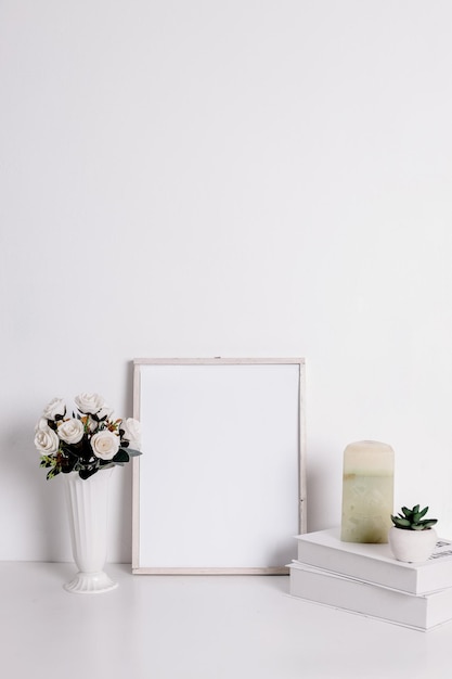 Maquete de quadro com flor de rosa artificial na vela de livros de vaso e flor suculenta na panela