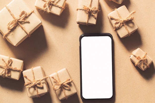 Maquete de smartphone com caixa de presente de ano novo com tela branca em branco e modelo de pinheiro de Natal