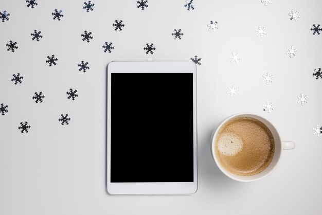 Maquete de tablet digital em fundo de inverno com flocos de neve e café