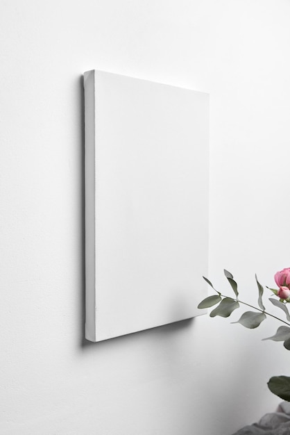 Maquete de tela branca pendurada na parede branca e buquê de rosas cor de rosa com tela em branco de eucalipto