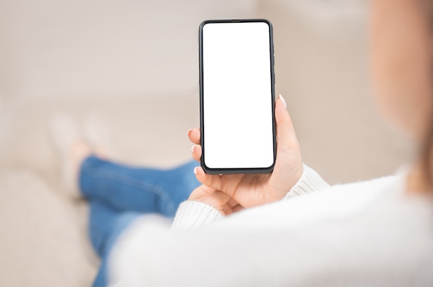 Maquete do celular em branco tela branca smartphonewoman mão segurando mensagens de texto usando o celular no sofá