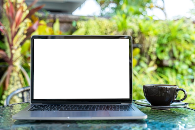 Maquete do computador portátil com tela vazia com xícara de café e smartphone na mesa do café ao ar livre tela branca