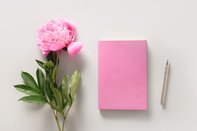 Maquete feminina criativa com caderno de flores de peônia de xícara de café para planejamento