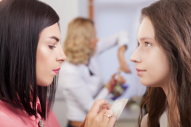 Maquiador profissional trabalhando com uma jovem bonita