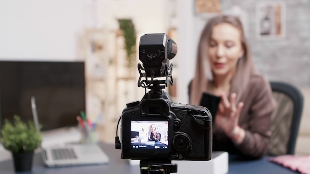 Maquiadora feminina gravando unboxing de um novo telefone. Foco seletivo na câmera