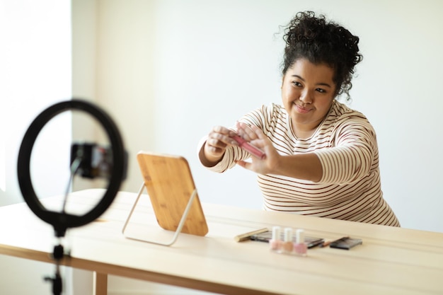 Maquiadora jovem muito acima do peso gravando vídeo mostrando batom