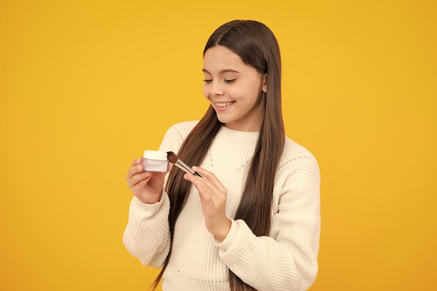 Maquiagem de beleza e cosméticos infantis Menina adolescente com pincel aplicando blush no rosto isolado em fundo de poço