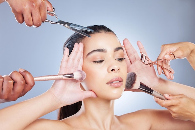 Maquiagem de salão e rosto de mulher com pincel em estúdio para beleza de bem-estar e cosméticos em fundo azul Mãos de cosmetologia e menina com pincéis para produtos e fundação de aplicação cosmética