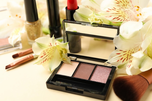 Maquiagem diferente cosméticos e flores sobre fundo bege