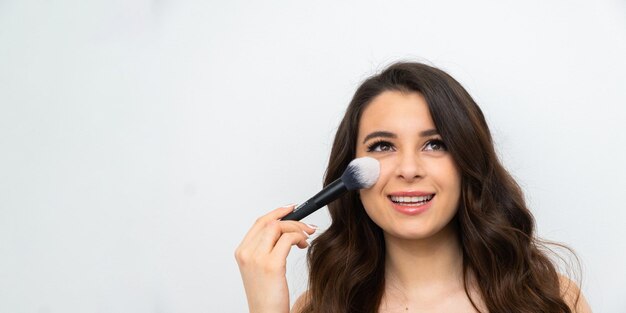 Maquiagem facial Jovem mulher sorridente aplicando blush com pincel cosmético