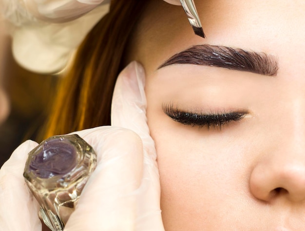 Foto el maquillador aplica pintura a las cejas. maquillaje permanente. teñido con pintura de henna.