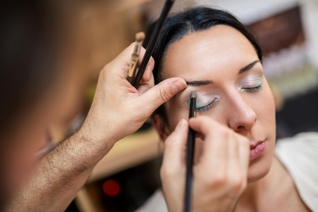 Maquillador aplicando la sombra de ojos al modelo.