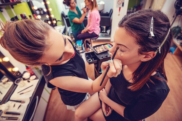 Maquillador aplicando la sombra de ojos al modelo.