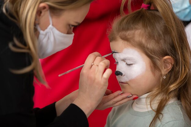 Un maquillador dibuja pintura facial en la cara de una niña