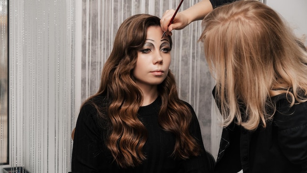 Un maquillador hace arte de maquillaje de ojos para una niña en un salón de belleza El concepto de celebrar Halloween Maquillaje inusual