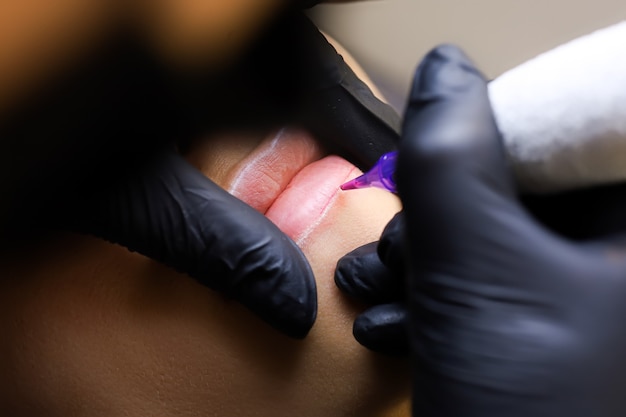 El maquillador permanente realiza la primera pasada de aplicar pigmento labial