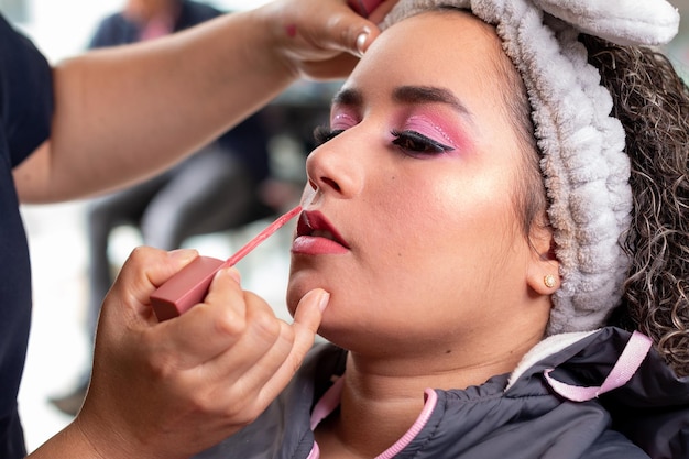 Maquillador profesional aplicando crema labial líquida a una mujer hermosa Salón de belleza profesional