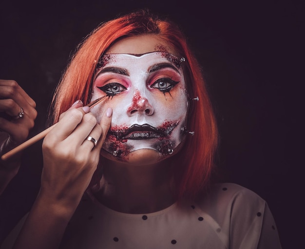 El maquillador talentoso está creando un arte especial de miedo de Halloween en la cara de la mujer.