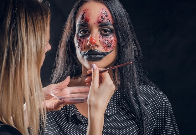 El maquillador talentoso está creando un arte especial de miedo de Halloween en la cara de la mujer.