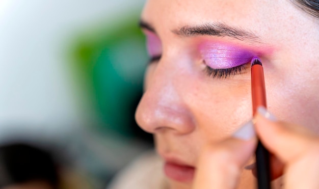 Maquilladora aplicando con pincel cosmético en la ceja de una mujer
