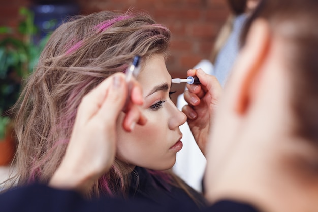 Maquilladora arreglando las cejas de la modelo con gel