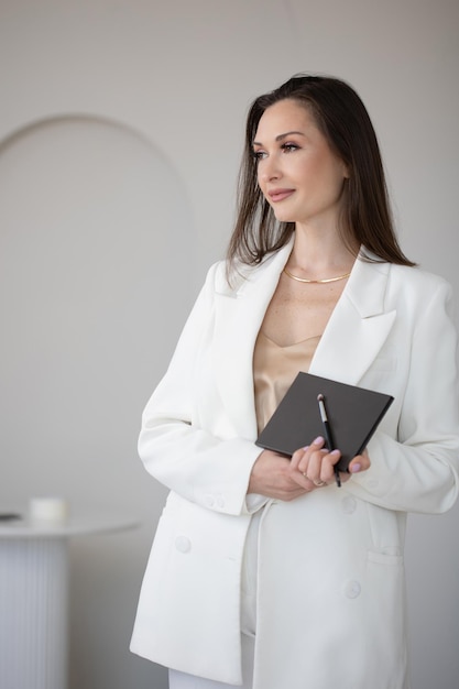 Foto maquilladora elegante de moda y belleza en una chaqueta blanca con pinceles de maquillaje en su negocio de manos
